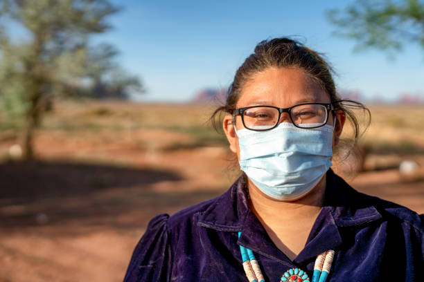A Young Navajo Woman Wearing A Protective Face Mask, Covid19, Living In Monument Valley, Arizona A native American teenager in her native costume wearing a face mask during the coronavirus, government shutdown navajo nation covid stock pictures, royalty-free photos & images
