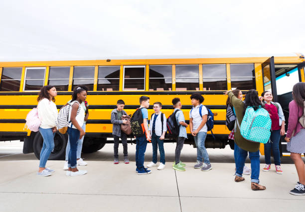 istock Students stand around waiting to board school bus 1223481648