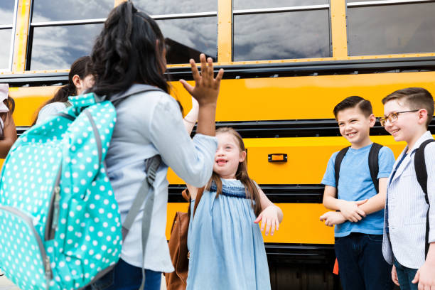 istock Standing by school bus, girls give high five 1223481649