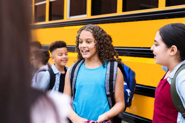 istock Diverse girls chat while waiting to board school bus 1223481699