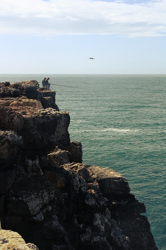 Local fishermen challenging the height of the cliffs practicing their hobby.