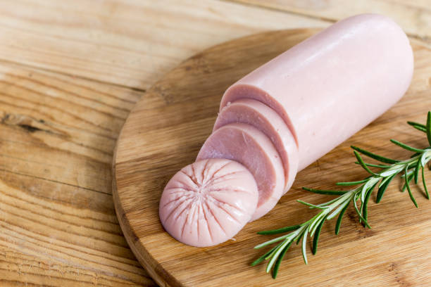 Sliced pork bologna salami with rosemary on the wooden board stock photo