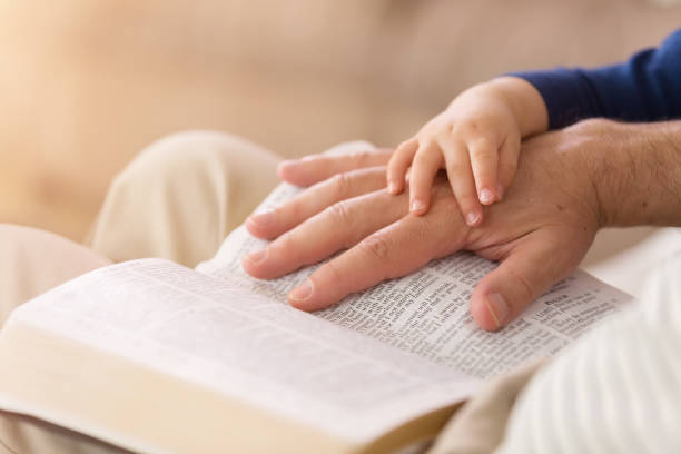 il nonno legge al bambino dalla bibbia - family bible foto e immagini stock