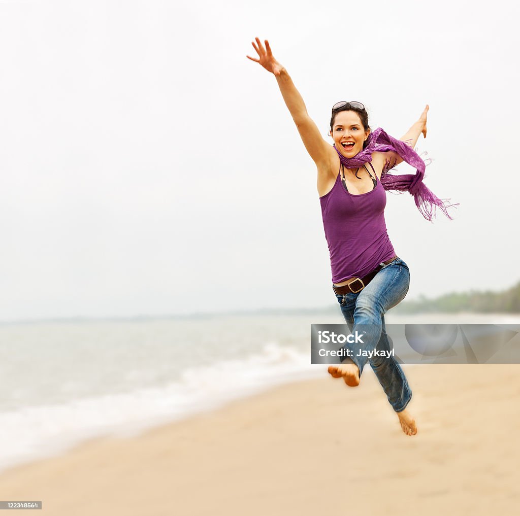 Beautiful young woman taking a great leap on the beach A beautiful energetic young woman taking a great leap on the beach Active Lifestyle Stock Photo