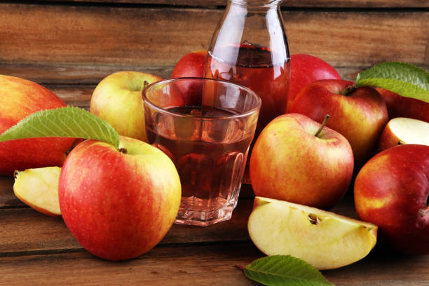 istock Apple cider drink and organic apples with leaves on table 1223487218
