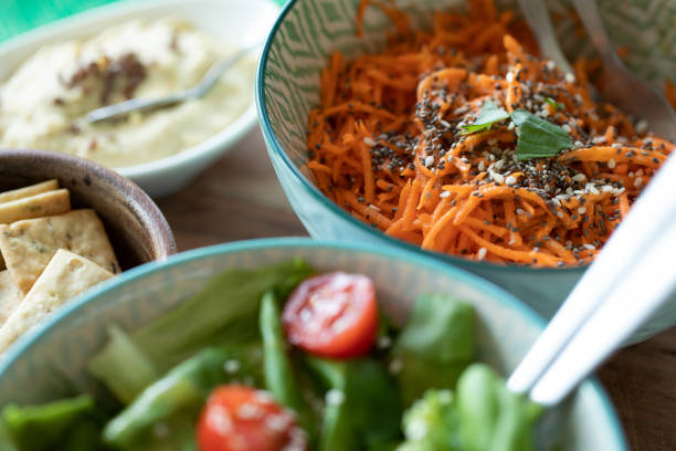 zbliżenie wegemteryjskiej diety wegańskiej z zieloną sałatką z pomidorami i nasionami chia posypane tartą sałatką z marchwi - vegeterian food zdjęcia i obrazy z banku zdjęć