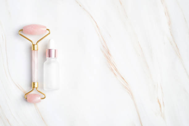 istock Face massage roller with serum or essential oil bottle on marble background. Flat lay, top view, copy space. Facial skin care, body treatment concept. 1223488155