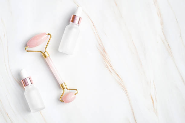 istock Face massage roller and two dropper bottle with essential oil on marble background. Flat lay, top view. Facial massage, spa relax, body treatment and skin care concept. 1223488163