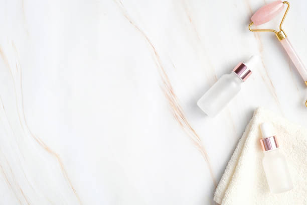 istock Flat lay composition with natural SPA cosmetics and equipment for face care. Top view transparent dropper bottles with organic essential oils, towel, face massage roller on marble background 1223488166