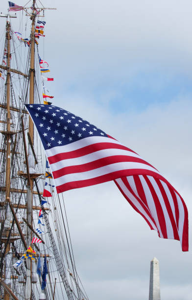 star-spangled banner billows softly off a sailing ship with revolutionary war monument in the distance - star spangled banner imagens e fotografias de stock
