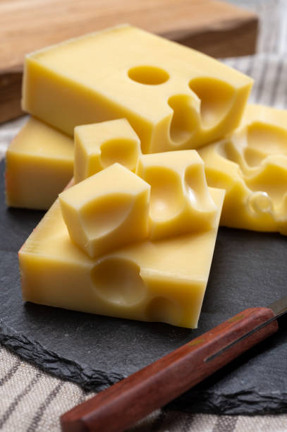 block of swiss medium-hard yellow cheese emmental or emmentaler with round holes and cheese knife - cheese emmental cheese switzerland grated imagens e fotografias de stock