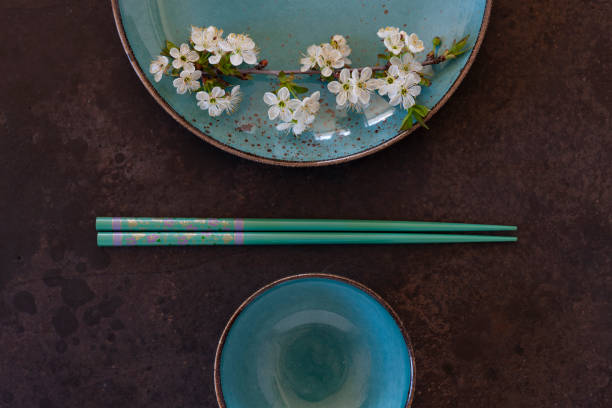 istock Spring floral Japanese food concept with blooming cherry tree branches on blue dish and serving with chopsticks on dark background 1223488671