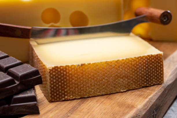 tasty swiss food, block of medium-hard yellow cheese emmental or emmentaler with round holes, matured gruyere and high quality milk chocolate - cheese emmental cheese switzerland grated imagens e fotografias de stock