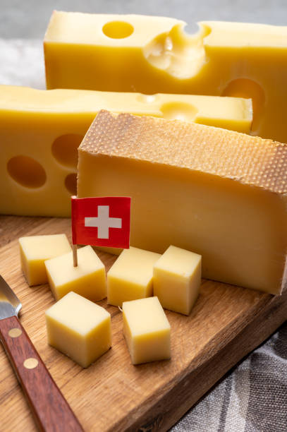 swiss cheeses, block of medium-hard yellow cheese emmental or emmentaler with round holes and matured gruyere. - cheese emmental cheese switzerland grated imagens e fotografias de stock