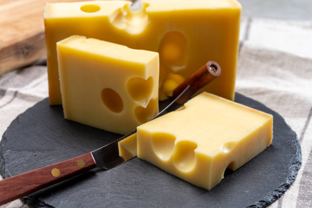 block of swiss medium-hard yellow cheese emmental or emmentaler with round holes and cheese knife - cheese emmental cheese switzerland grated imagens e fotografias de stock