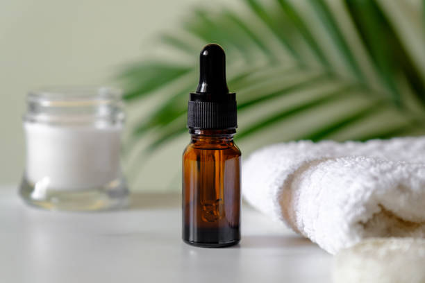istock Serum or essential oil bottle with moisturizer and towel, palm leaf on the background. Clear amber glass dropper bottle with natural organic cosmetic, SPA products, skin treatment, body care concept. 1223488759