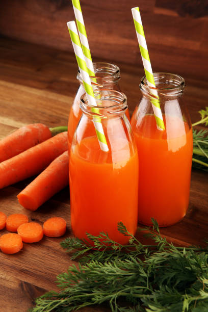 istock Fresh carrot juice in bottles with organic carrots on table. Vegetable juice set 1223489727