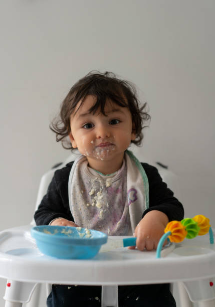 istock Cute baby boy in a mess learning self feeding, sitting in a high chair 1223491697