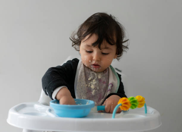 istock Cute baby boy in a mess learning self feeding, sitting in a high chair 1223491699