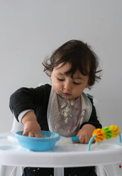 istock Cute baby boy in a mess learning self feeding, sitting in a high chair 1223492328