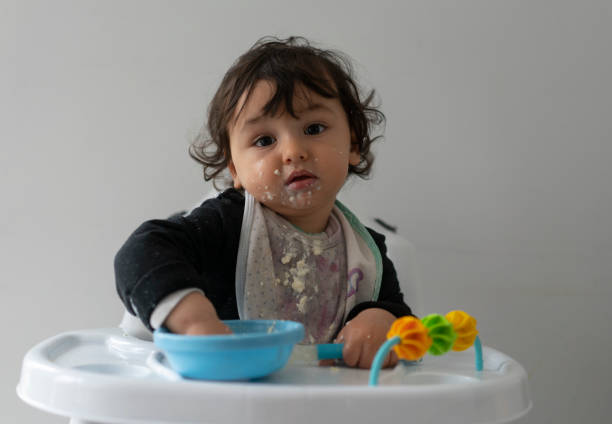 istock Cute baby boy in a mess learning self feeding, sitting in a high chair 1223492330