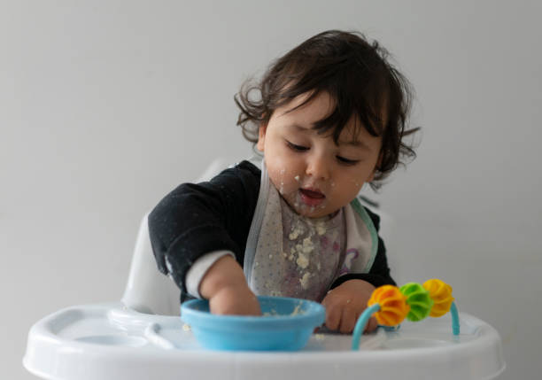 istock Cute baby boy in a mess learning self feeding, sitting in a high chair 1223492564