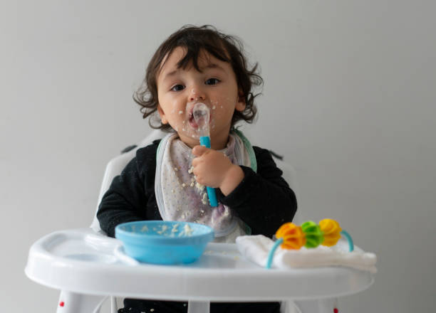 istock Cute baby boy in a mess learning self feeding, sitting in a high chair 1223492797