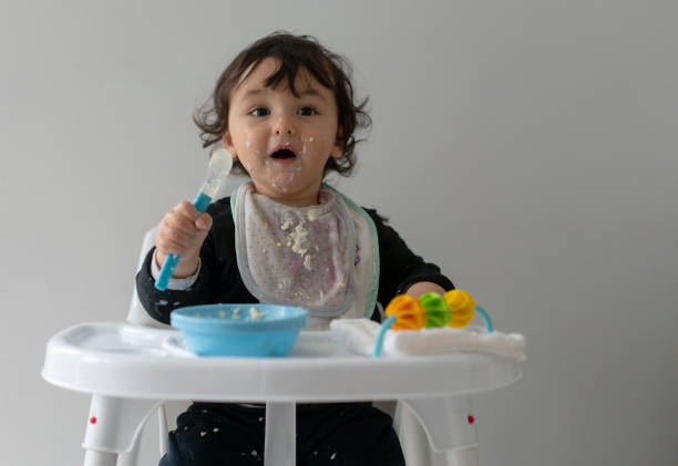 istock Cute baby boy in a mess learning self feeding, sitting in a high chair 1223492833