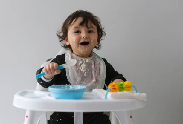 istock Cute baby boy in a mess learning self feeding, sitting in a high chair 1223492911