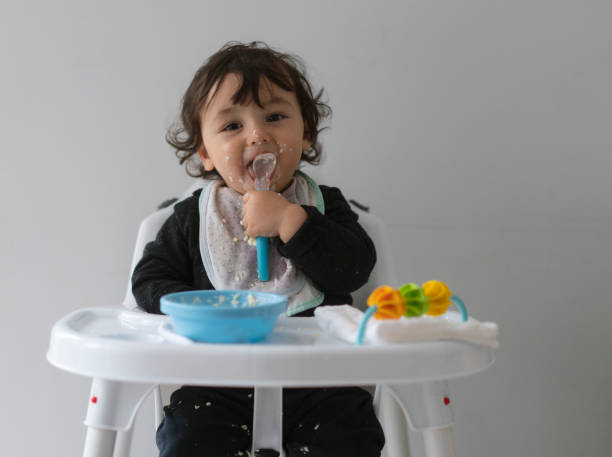 istock Cute baby boy in a mess learning self feeding, sitting in a high chair 1223492931