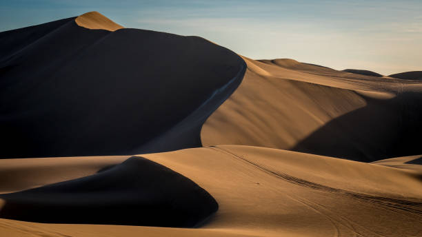 istock Path along stunning beige dunes outside in the desert with soft sunlight throwing shadows in the peaceful dusk. 1223495288