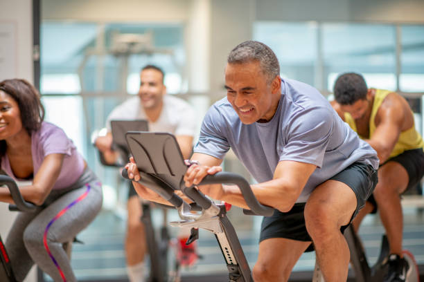 starszy mężczyzna podczas ćwiczeń - spinning gym cycle cycling zdjęcia i obrazy z banku zdjęć