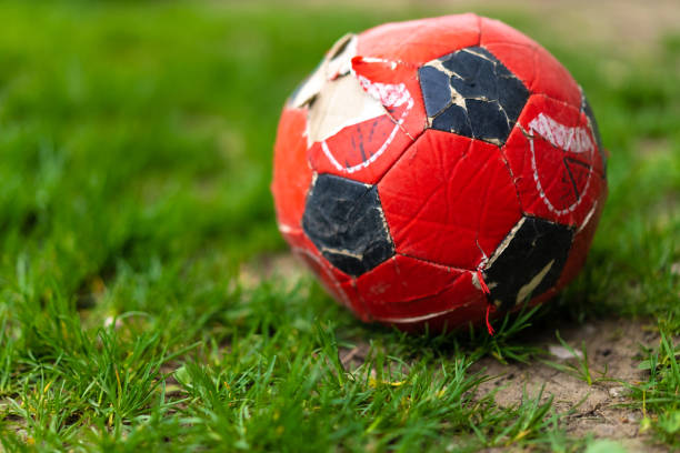 A torn soccer ball lies on the grass