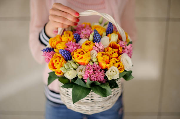istock Creative basket with bright spring flowers in the woman's hands 1223503810
