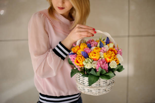istock Woman holds in her hands a decorative basket with different spring flowers. 1223503900