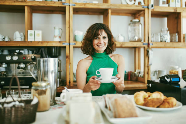 istock Smiling Cafe Worker Holding Cup of Coffee Behind Counter 1223507482