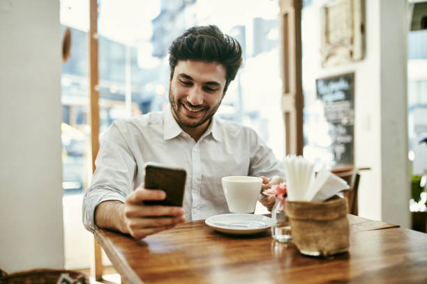 istock Smiling Young Man Enjoying Coffee Break and Smart Phone 1223507483