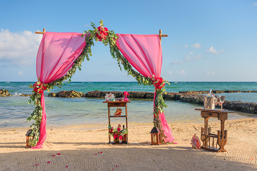 Wedding arch on the beach and tropical beach. Fabrics, bamboo, decor of flowers.