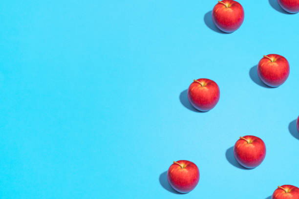 istock Summer abstract trendy fresh concept. red Apple pattern on bright light blue background, copy space. Minimal flat lay food texture 1223509816
