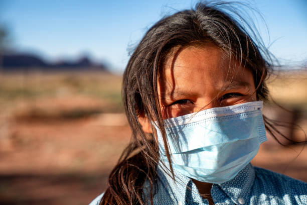 A Young Boy Wearing A Mask Over His Mouth And Nose Because Of The Coronavirus Pandemic On The Navajo Reservation In Arizona A young Navajo boy living in Monument Valley Arizona wearing a mask to protect himself from getting Covid19 curfew stock pictures, royalty-free photos & images