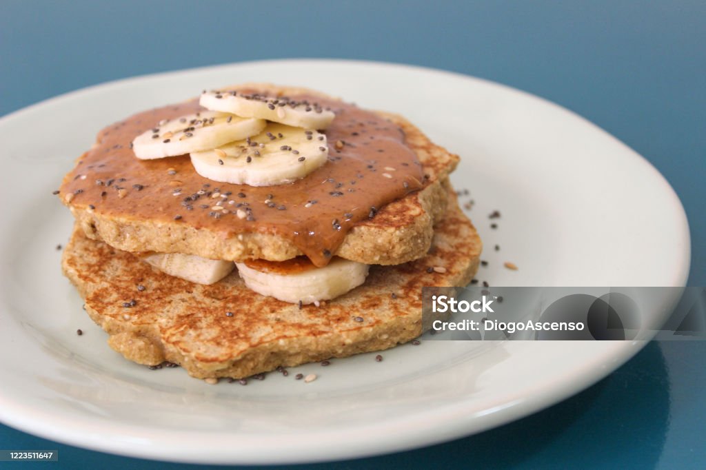Oat pancakes with peanut butter and banana Oat pancakes with peanut butter and banana on a blue plate Pancake Stock Photo