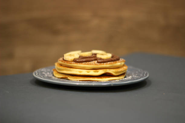 Pancakes with chocolate and banana on blue plate Pancakes with chocolate and banana on blue plate on dark wooden background apple cinnamon pancake stock pictures, royalty-free photos & images