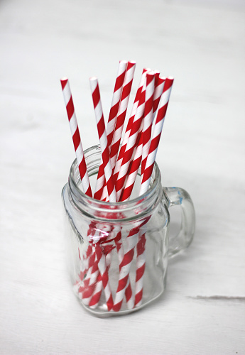 Paper straws red and white in glass cup with white background vertical