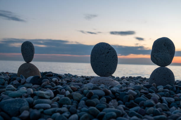 Summer is coming soon in a pandemic. Deserted city beach on the Black Sea. Sculptures of stones, a symbol of people. Stone people. Imitation of lovers. Art installation from pebbles. Meditation at sea.
