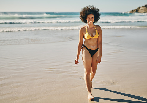 Full length portrait of an attractive young woman enjoying a day out on the beach alone