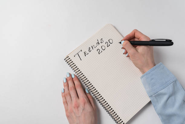 istock Trends 2020 handwritten text on copybook. Female hand writing in notebook. Planning concept 1223517478