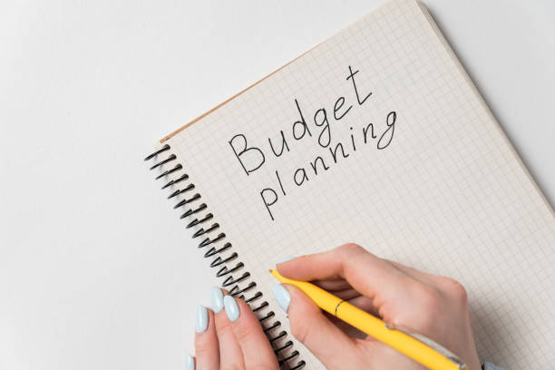 istock Budget planning concept. Female hand holding pen and writing in notebook. White background 1223517518