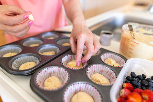 Woman putting cheese on muffins before baking