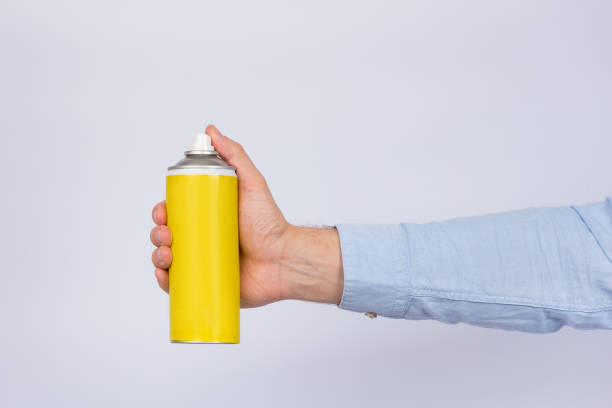 istock Male hand holding yellow spray bottle on white background. Copy space, mock up. Side view 1223519974