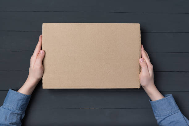 istock Cardboard box in children's hands on black background. Top view. Copy space 1223520921